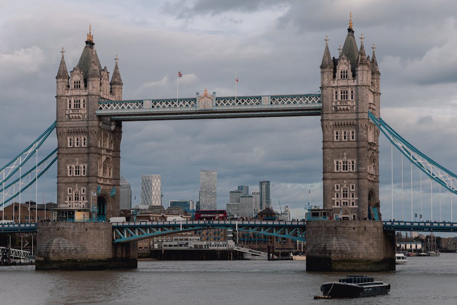 A Thameslink train traveling on an elevated railway track above a street in London, with modern black glass apartment buildings on the right and traditional brick residential buildings with chimneys o