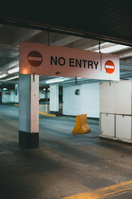 Close-up of a yellow warning sign attached to a metal pole, indicating 'Parking suspension' as part of house removals or home relocation logistics. The sign is illuminated by natural light with blurre